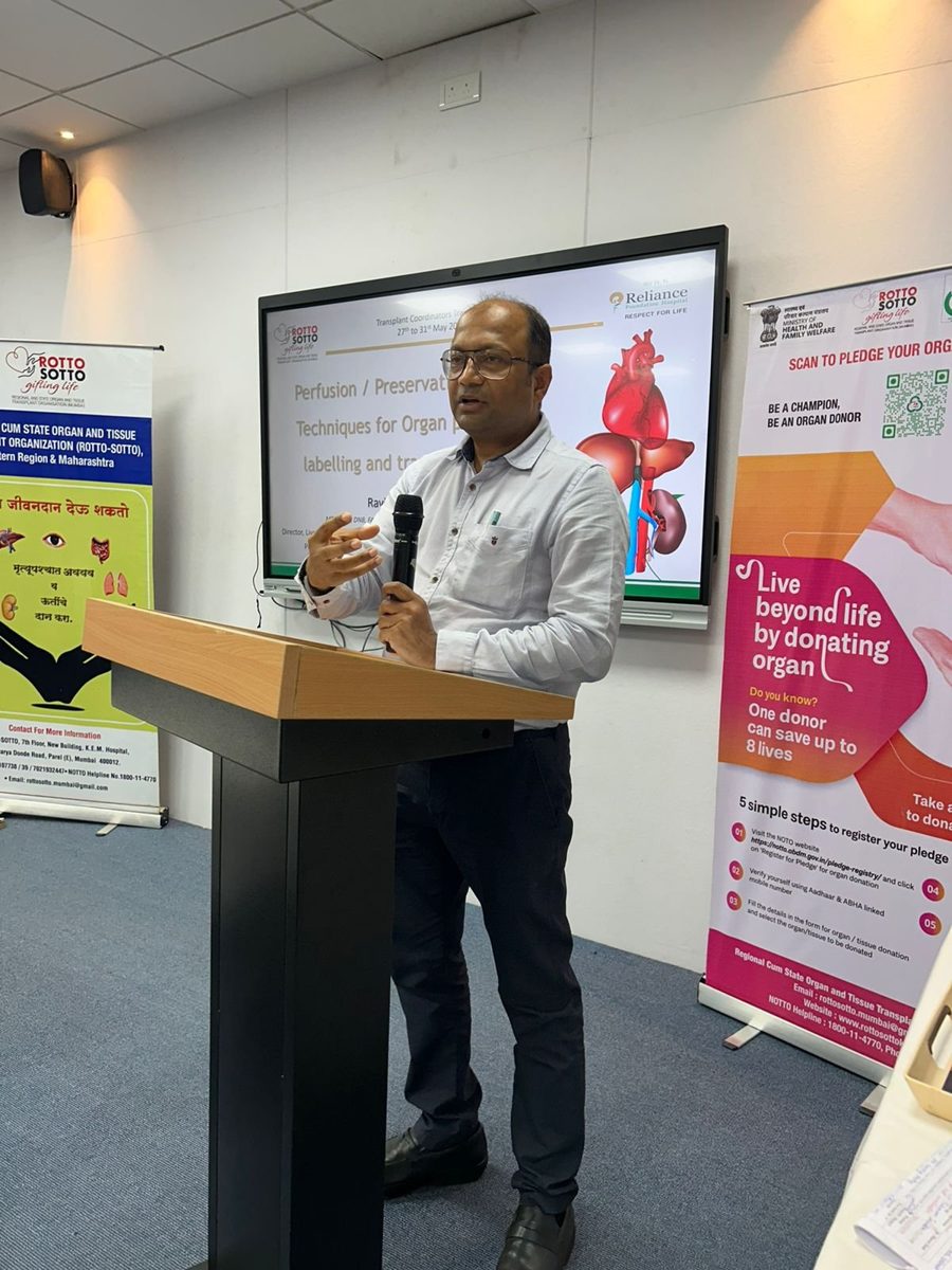 Dr. Mohanka speaking at a podium beside organ-donation banners